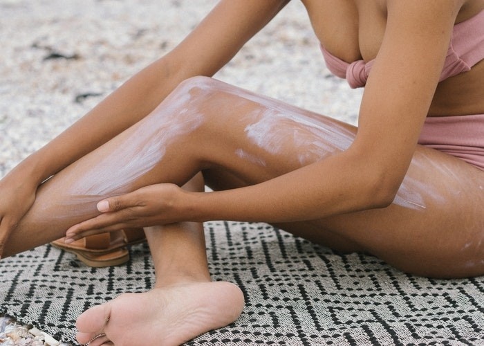 Une femme met de la crème solaire sur la plage