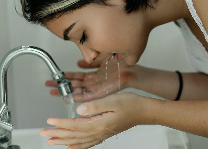 Una mujer lavándose la cara com agua