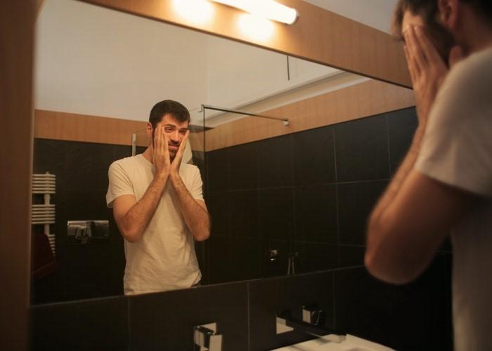 Un hombre con síntomas de depresión se mira al espejo