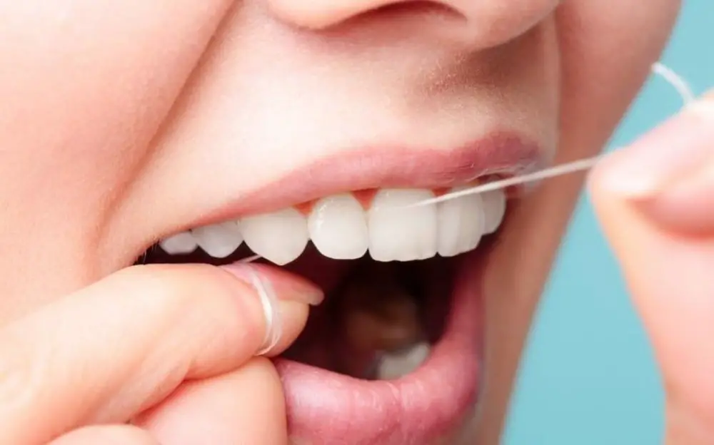 mujer usando hilo dental en los dientes