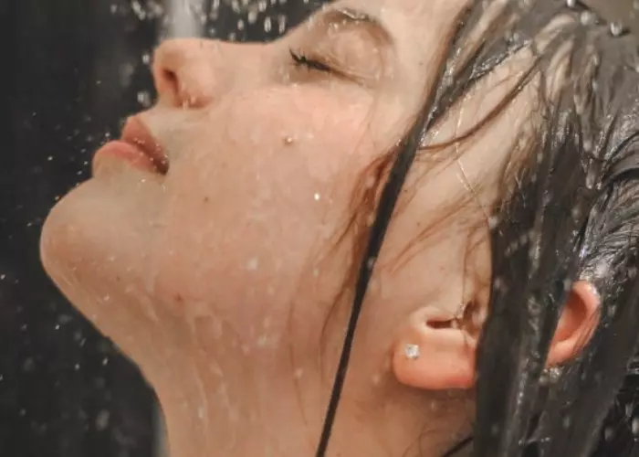 Una mujer lavando sus oídos en la ducha