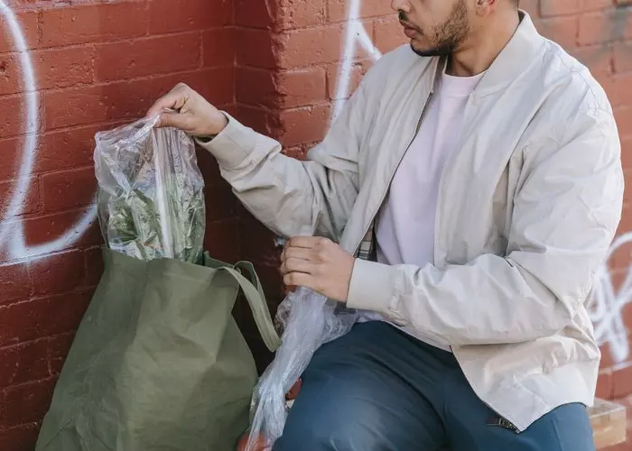 Un hombre sacando su compra en bolsas de plástico