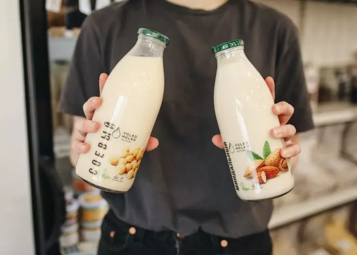 رجل يعرض نوعين من الحليب النباتي