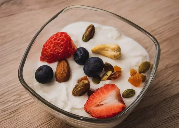 Un bol de cristal con yogurt griego, frutas y frutos secos