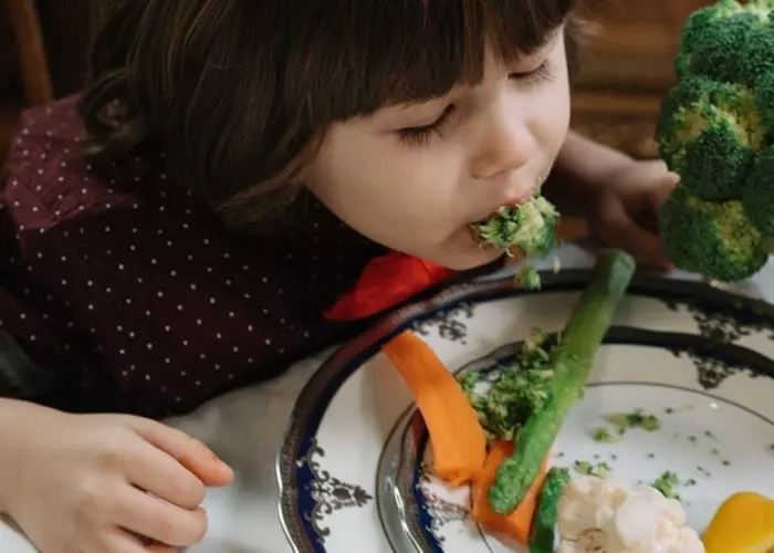 En liten pojke som äter broccoli