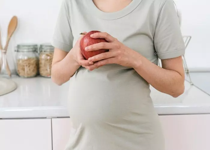 En gravid kvinne med forstoppelse spiser et eple