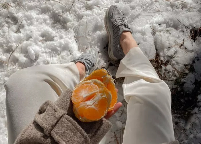 Una chica comiendo mandarinas en la nieve