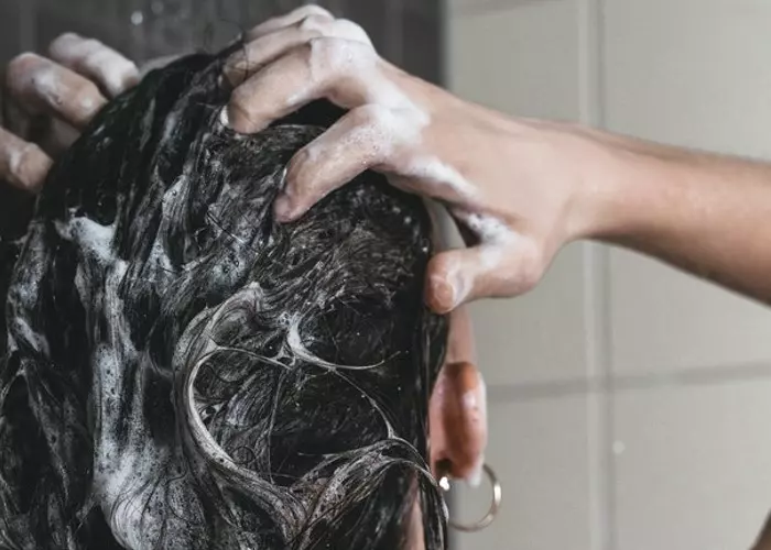 En kvinde, der vasker sit hår med luseshampoo